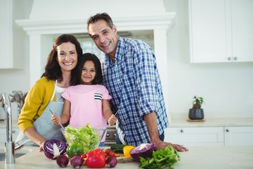 Portrait of parents and daughter preparing salad in kitchen