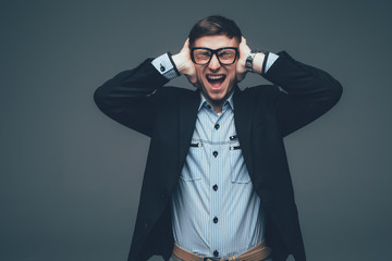 Portrait of a serious young man covering both ears with hands