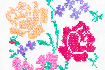 Handmade embroidery in the old-style multi-colored flowers on a woven fabric