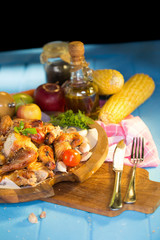 Whole roasted chicken garnished with tomatoes and apple on blue table.