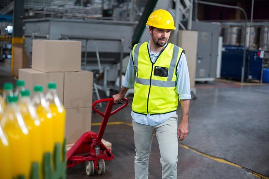 Factory worker pulling trolley of cardboard boxes - Powered by Adobe