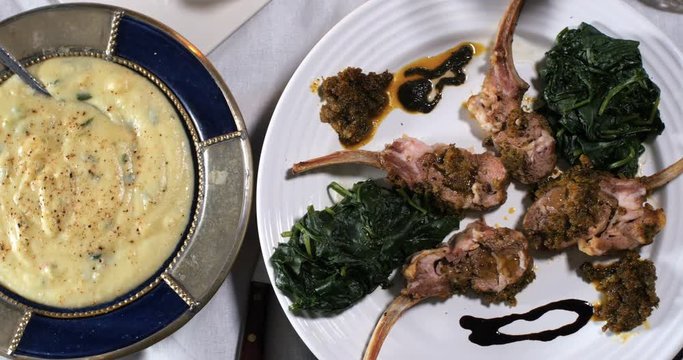 Dolly top down view of a rack of lamb with crusted mint sauce, with spinach and mashed potatoes