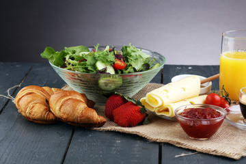 breakfast on table with salad, croissants, coffe and juice
