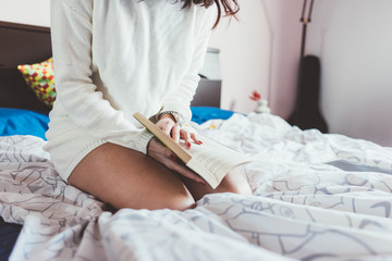 Midsection of young woman reading book lying on her bed - student, education, relaxing concept