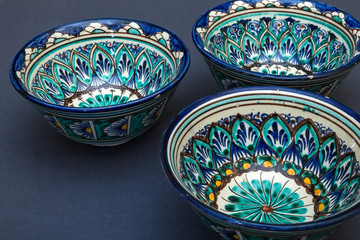 Ethnic Uzbek ceramic tableware on the gray background. Decorative ceramic cups with traditional uzbekistan ornament.