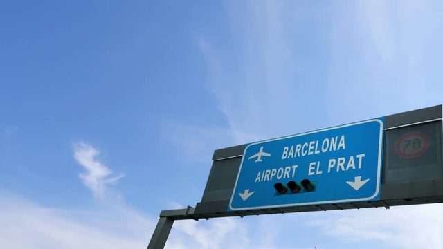 plane flying above barcelona airport signboard