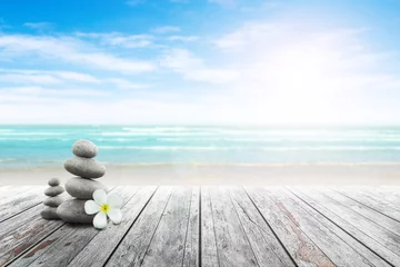 Gartenposter Stapel von Kieselsteinen und Plumeria am Strand auf einer Holzoberfläche. Konzept Zen, Spa, Sommer, Strand, Meer, Entspannung. © Akura Yochi