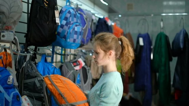 Young girl consultant in a specialty store for the tourism picks backpack.