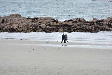 Un couple se promène sur une plage de Bretagne en hiver