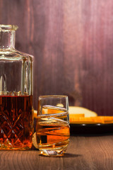 glass short of whiskey standing on the wooden table beside her decanter and stopper, in the...
