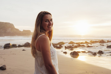 Portrait of smiling woman standing at beach during sunset