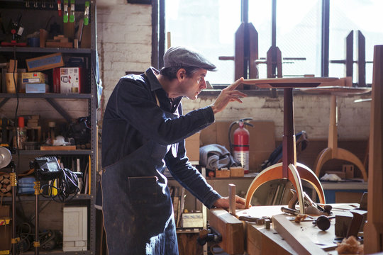 Carpenter examining wooden stool in workshop