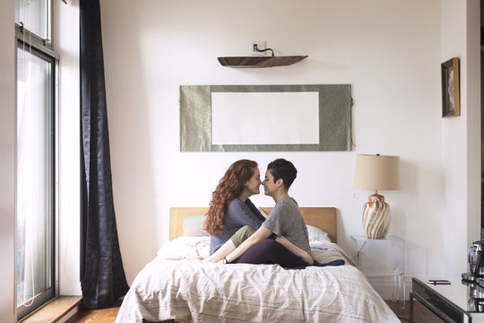 Side view of couple rubbing noses on bed