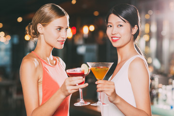 Two Smiling Women with Cocktails in Restaurant