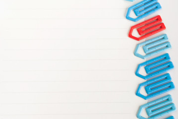 many blue and one red paper clip on a white paper  with space for text