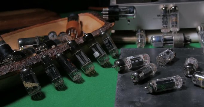Dolly close up view of a collection of vintage vacuum tubes (valves) tor music amplifiers manufactured in the forties
