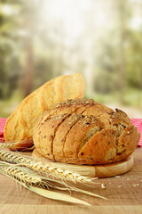 Bread and wheat on wooden table.