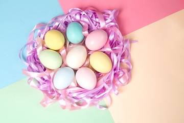 Fototapeta na wymiar Colorful easter eggs in nest from tapes on a color background