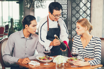 Asian Waiter Offering Red Wine to Young Couple