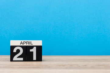 April 21st. Day 21 of month, calendar on wooden table and blue background. Spring time, empty space for text