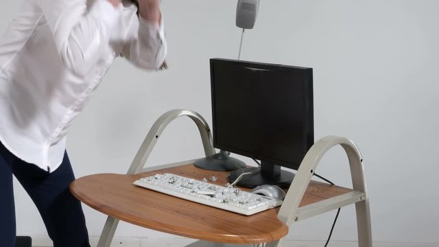 Crazy woman office worker destroying computer with sledge hammer trying to reduce stress