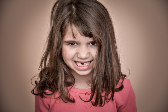 Portrait of an angry and frowning  toothless young girl