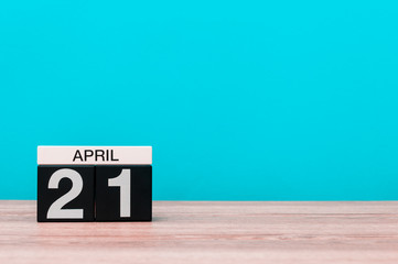 April 21st. Day 21 of month, calendar on wooden table and turquoise background. Spring time, empty space for text