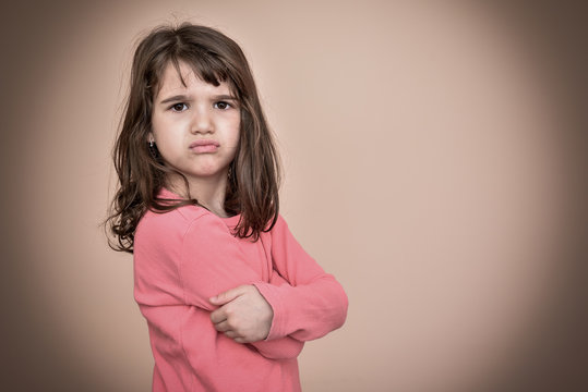 Angry and pouting cute young girl with crossed arms