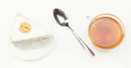 Spoon, piece of cake,  tea lying on a  surface.
