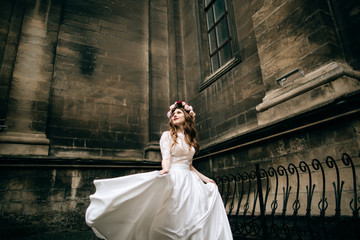 beautiful bride in a wreath and a white wedding dress walking the streets of old European city © Yevhenii Kukulka