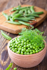 Green peas in wooden bowl on  rural background