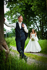 Groom is standing on the oak tree after the marriage with his cute and pretty bride. the bridegroom...