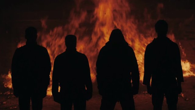 Four man silhouette standing on fire flames background. Silhouette men standing of fire background. Four men standing fire burning. Male silhouettes standing on flames fire