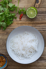 Asian rice noodles in a white bowl. Wooden background.
