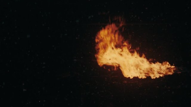 Flame fire blow on dark background. Blowing fire flame on night background. Flames fire blowing on black background. Fire flames on night snow falling. Bonfire at winter night. Campfire burning