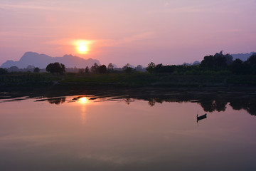 Fototapeta premium Lonely wooden boat reflecting in the river at the sunset, Myanmar.