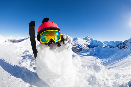 Snowman in helmet and mask against mountain scene