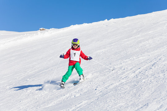 Kid skiing with safety helmet, goggles and poles