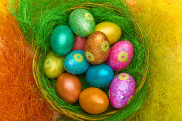 Happy Easter. Colorful Easter eggs in a basket on the artificial grass