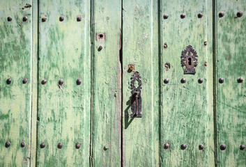 green wooden door with ancient metallic ornaments