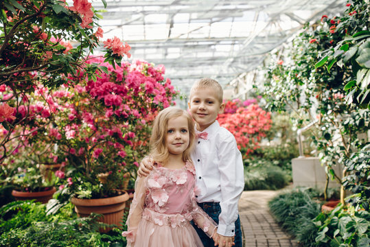Little boy and girl are walking in a blooming garden
