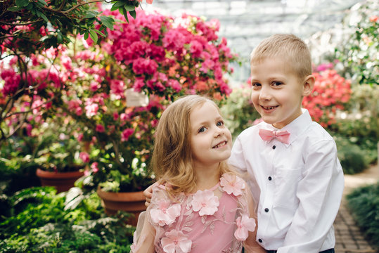 Little boy and girl are walking in a blooming garden