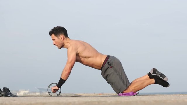 Athletischer Mann macht Training mit AB-Roller Bauchtrainer 