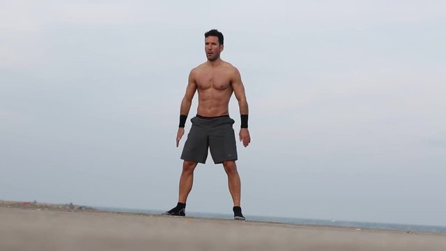 Athletischer Mann macht Squats am Meer