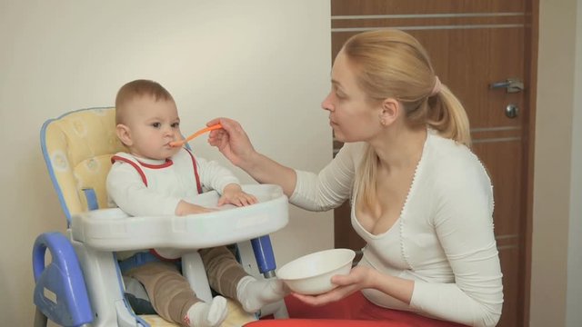 Mom feeds a mischievous little child with a spoon of vegetable puree