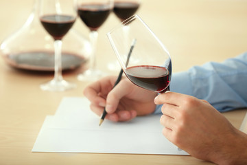 Sommelier estimating red wine in wineglass at tasting - obrazy, fototapety, plakaty