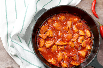 Frying pan with delicious chicken tikka masala on wooden table