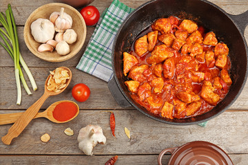 Frying pan with delicious chicken tikka masala on wooden table