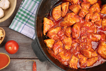 Frying pan with delicious chicken tikka masala on wooden table