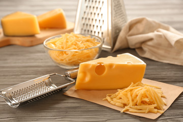 Tasty cheese and grater on wooden table